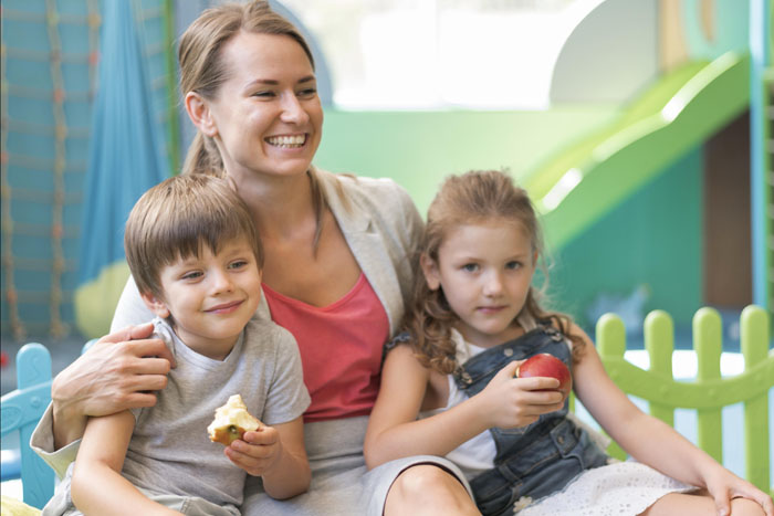 medium-shot-happy-teacher-holding-kids